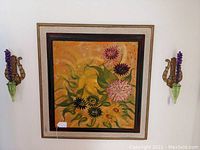 Frontal view of a framed floral painting flanked by the pair of green depression glass wall vases mounted on gold lyre-shaped brackets, showing overall size and mounting.