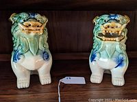 Front view showing detailed facial features and coloration of the two lion figurines placed side by side.