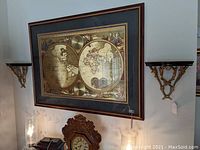 Pair of wood and brass display shelves mounted on wall beneath framed map artwork.