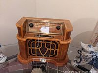 Front view of vintage-style radio cassette player with a wooden frame, two tuning knobs, frequency window, and decorative speaker grill.