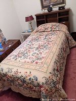 Twin bed fully dressed with floral bedding and visible headboard setup
