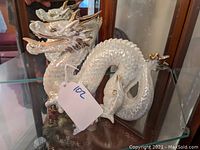 Side view showing curled body and gold details on dragon's face, horns, claws, and tail.