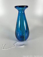 Blue teardrop-shaped glass vase with yellow strands inside, shown from one angle