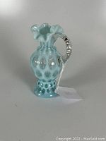 Front side view showing the blue opalescent glass and coin spot pattern with clear twisted handle and ruffled rim