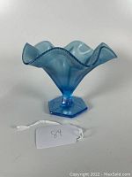Side view of blue stretch glass ruffled edge footed candy bowl showing shape, ruffled rim, texture.