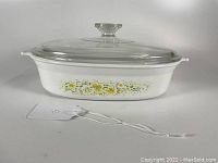 Front angle view of the white oval casserole dish showing the Corning Ware April floral pattern and glass lid.
