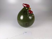 Green egg-shaped pottery chicken/rooster figurine with red comb and wattle, side angle showing body and head details