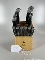 Front view of J.A. Henckels wooden knife block filled with knives, including steak knives with some handle damage.