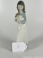 Porcelain figurine of girl holding a dog shown from front, highlighting details and condition.