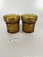 Front view of matched pair of amber-colored Indiana Glass Company fairy lamps with detailed stars and bars pressed pattern and scalloped rims.