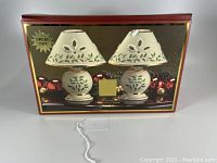 Photo showing the two Lenox porcelain holiday tea light lamps in the original box with decorative background.