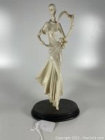 Front view of the elegant woman sculpture on black base showing flowing dress and flower detail.