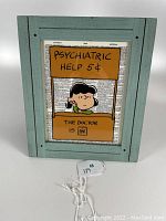 Full view of vintage Peanuts print framed with Lucy sitting at her Psychiatric Help Booth superimposed on a dictionary page.