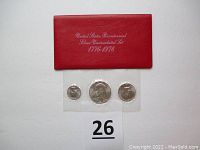 Red folder with United States Bicentennial Silver Uncirculated Set 1776-1976 inscription, three coins in a plastic sealed strip shown beneath.