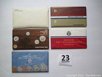 Photo showing five original United States Mint coin set packages from 1981, 1984, 1985, 1987, and 1991 arranged on a white surface.