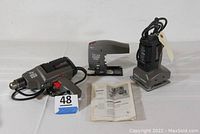 Full set including drill, saber saw, orbital sander, instruction manual laid out on white surface.