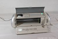 White Cricut Expressions electronic die-cutting machine with front compartment open showing rollers.