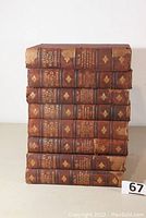 Front view of the 8 volumes stacked, showing titles and condition of spines.