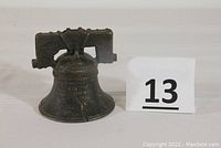 Front view of the antique cast iron Liberty Bell bank showing raised text and overall shape