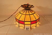 Full view of the stained glass hanging lamp showing the cream, red, and gold glass panels, the scalloped bottom edge, and wiring for ceiling installation.