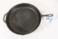 Top view of a large round cast iron skillet showing its smooth cooking surface and pouring spout on the side.