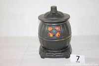 Full view of the black ceramic cookie jar shaped like a pot belly stove with orange and yellow details