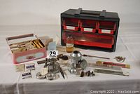 Full view of watch parts and tools including box full of new main springs in packaging, Electro-Vice, crystal changer, clock oil bottle, movement holders, watch bands, and carrying case with multiple drawers.