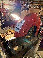Side and top view of the 14-inch cut off saw showing red blade guard, black handle, and metal base with rust spots. Also shows vise grip next to saw.