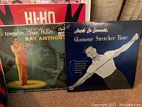 Two vintage vinyl records shown with covers: Ray Anthony's 'I Remember Glenn Miller' and Jack La Lanne's 'Glamour Stretcher Time'. Covers have mid-1900s styled photos and artwork.