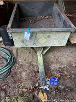 Front elevated view showing rectangular lawnmower cart interior and metal tongue with rust.