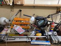 Overall view showing multiple tools, electric tubes organizer, magnifying lamp, tripod, cans, and handheld devices.