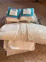 Shows two packages of Hobbs Heirloom 80/20 cotton/polyester batting, two pillow forms, and several patterned chair pads in the background.