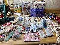 Overview photo showing variety of sewing patterns, Velcro, elastic, sequins, pincushion, and packaged supplies arranged on countertop.