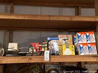 Shelf with various boxed items including halogen bulbs, four light bulbs boxes labeled Ionolite, security light boxes, and other boxed electronic parts.
