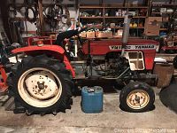 Side view of Yanmar YM1500 tractor showing rear tire, front wheel, engine area and fuel can on floor