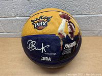 Front side of the basketball showing Phoenix Suns logo, Devin Booker's signature, name and NBA logo