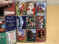 Photo showing multiple NFL Christmas and Santa football cards in binder sleeves with colorful seasonal artwork and player images.