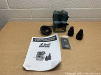 Photo showing Drill Doctor unit, power cord, two collets, manual, and small parts in plastic bag.