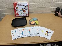 Full lot display with game box, pebble pieces in a plastic bag, black stacking tray, and game cards laid out on table.
