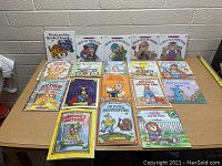 Photo of entire lot of 16 children's books spread out on table showing cover titles and artwork.