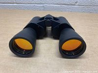 Front view of black Optic 250 binoculars showing large yellow coated lenses