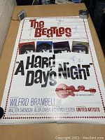 Full view of the Beatles A Hard Day's Night poster laid flat on a cardboard surface with digital cameras on corners.