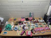 Table displaying large assortment of girls' toys, hair scrunchies, clips, and other small accessories spread out with good lighting.