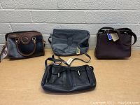 Four purses arranged side by side on a flat surface, showing overall size and appearance including tags on some purses.