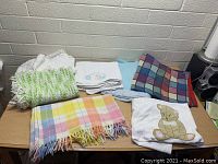 Photo of assorted baby blankets on a table in various colors and materials