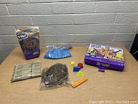 Wide view of lot showing both bags of kinetic sand, boxed set, sand molds, and shaping tools.