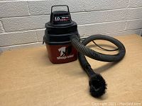 Front view of the mini Shop Vac showing the 1.0 Peak HP wet/dry vacuum label, the main body, and attached hose with circular brush attachment.