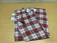 Photo showing folded women's sleep pants with red and white plaid pattern and Arizona Cardinals logo on pocket.