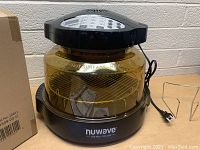 NuWave Oven overall view showing black base, large clear glass cooking bowl, power cord, and internal wire rack.