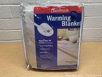 Front view of Sunbeam King Size Warming Blanket packaging showing product features and brand.